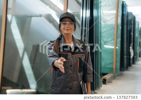 Giving hand to shake. Woman is in the window making factory Giving hand to shake. Woman is in the window making factory 137827383