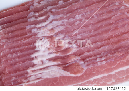 Bacon cooking sounds. Morning warmth indicated by freshly sliced bacon sizzling in pan. Thin slices of bacon hint at cozy breakfast filled with aroma and anticipation 137827412