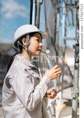 Thorough health management at construction sites. Female workers prevent heatstroke by staying hydrated and taking adequate rest. Thorough health management at construction sites. Female workers prevent heatstroke by staying hydrated and taking adequate rest. 137827523
