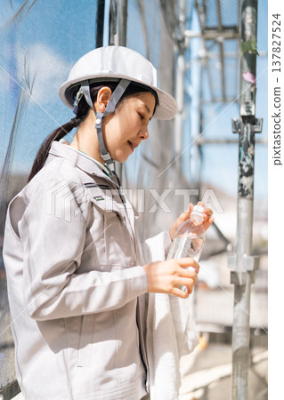 Thorough health management at construction sites. Female workers prevent heatstroke by staying hydrated and taking adequate rest. Thorough health management at construction sites. Female workers prevent heatstroke by staying hydrated and taking adequate rest. 137827524