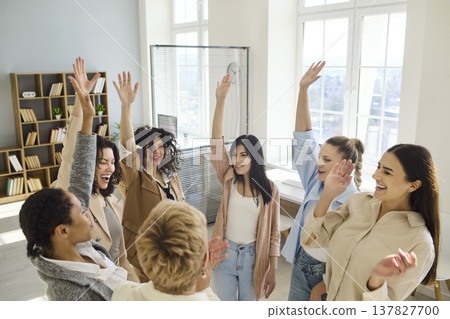 Diverse businesswomen raising hands cheering in office celebrating team success Diverse businesswomen raising hands cheering in office celebrating team success 137827700