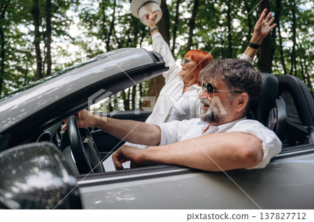 Positive facial expression. Senior couple driving convertible cabriolet car Positive facial expression. Senior couple driving convertible cabriolet car 137827712