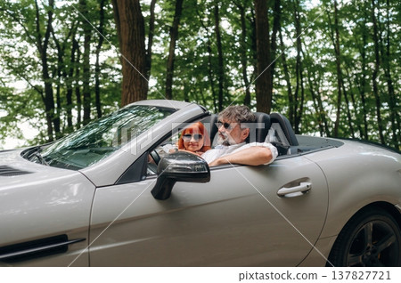 Road near the trees. Senior couple driving convertible cabriolet car 137827721