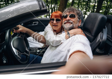 Time for a selfie. Senior couple driving convertible cabriolet car Time for a selfie. Senior couple driving convertible cabriolet car 137827722