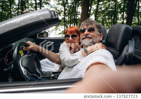 Time for a selfie. Senior couple driving convertible cabriolet car Time for a selfie. Senior couple driving convertible cabriolet car 137827723