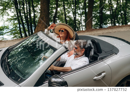 Wearing sunglasses, side view. Senior couple driving convertible cabriolet car 137827732