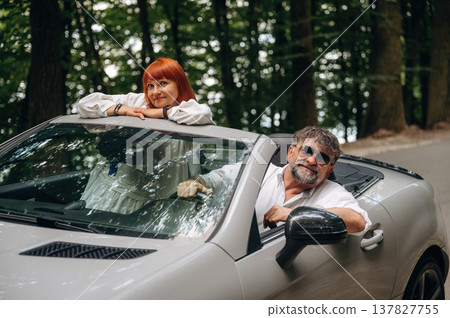 Riding and smiling. Senior couple driving convertible cabriolet car Riding and smiling. Senior couple driving convertible cabriolet car 137827755