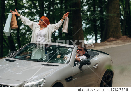 Shopping bags are in hands. Senior couple driving convertible cabriolet car 137827756