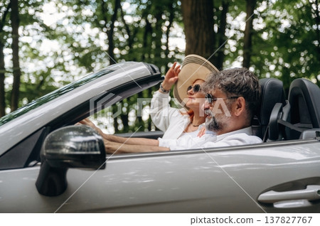 Enjoying the ride, in the hat, vacation. Senior couple driving convertible cabriolet car 137827767