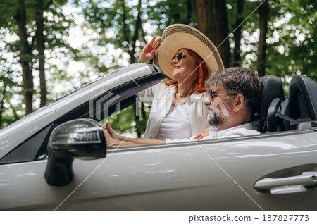 Enjoying the ride, in the hat, vacation. Senior couple driving convertible cabriolet car Enjoying the ride, in the hat, vacation. Senior couple driving convertible cabriolet car 137827773