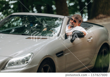 Focused on the road. Stylish senior man is in convertible cabriolet car Focused on the road. Stylish senior man is in convertible cabriolet car 137827800