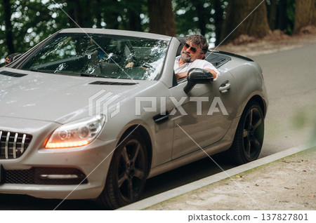 Focused on the road. Stylish senior man is in convertible cabriolet car Focused on the road. Stylish senior man is in convertible cabriolet car 137827801