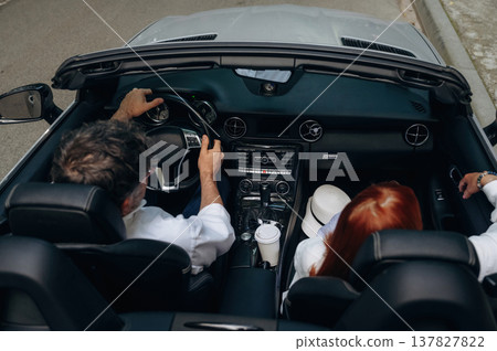 Rear view of senior couple that is driving the convertible cabriolet car 137827822