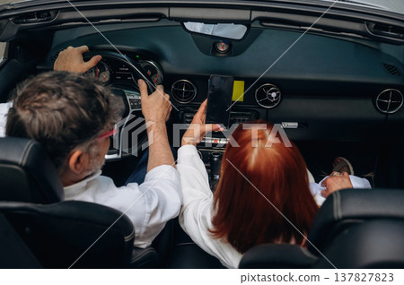Rear view of senior couple that is driving the convertible cabriolet car 137827823
