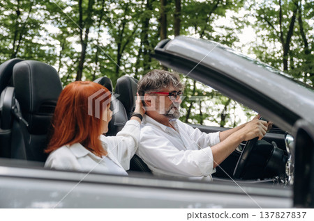 Touching the hair, conception of love and care. Senior couple driving convertible cabriolet car 137827837