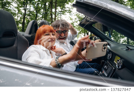 Making the selfie. Senior couple driving convertible cabriolet car Making the selfie. Senior couple driving convertible cabriolet car 137827847