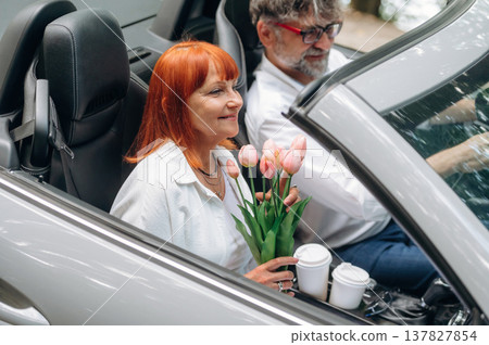 Flowers in hands. Senior couple driving convertible cabriolet car 137827854