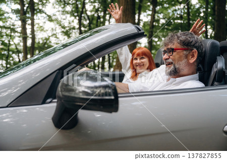 Riding and smiling. Senior couple driving convertible cabriolet car 137827855