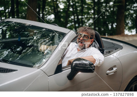 Vintage pilot glasses. Stylish senior man is in convertible cabriolet car Vintage pilot glasses. Stylish senior man is in convertible cabriolet car 137827898