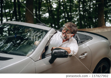 Retro aviator pilot glasses. Stylish senior man is in convertible cabriolet car Retro aviator pilot glasses. Stylish senior man is in convertible cabriolet car 137827902