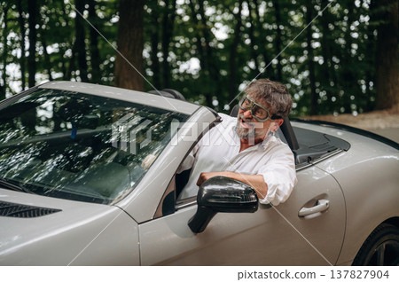 Retro aviator pilot glasses. Stylish senior man is in convertible cabriolet car Retro aviator pilot glasses. Stylish senior man is in convertible cabriolet car 137827904
