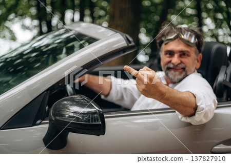 Offensive behavior, showing middle finger. Stylish senior man is in convertible cabriolet car Offensive behavior, showing middle finger. Stylish senior man is in convertible cabriolet car 137827910