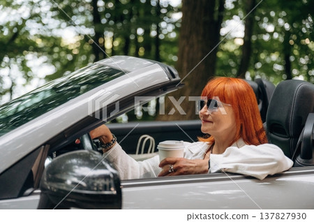 Side view of woman that is driving convertible cabriolet car Side view of woman that is driving convertible cabriolet car 137827930