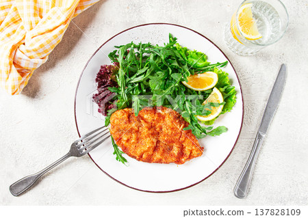 Milanese chicken, Crispy breaded chicken served, with fresh herbs, and lemon wedges, Milanese chicken, Crispy breaded chicken served, with fresh herbs, and lemon wedges, 137828109