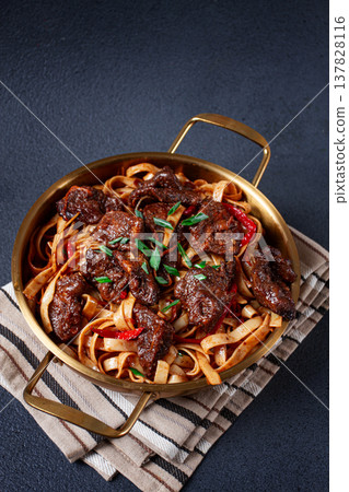Udon noodles with beef in Mongolian style, with green onions and vegetables, homemade, on a dark background, 137828116