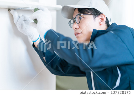On-site inspection for home renovation. An engineer accurately measures the wall dimensions using a measuring tape. On-site inspection for home renovation. An engineer accurately measures the wall dimensions using a measuring tape. 137828175