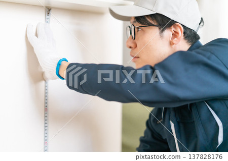 On-site inspection for home renovation. An engineer accurately measures the wall dimensions using a measuring tape. On-site inspection for home renovation. An engineer accurately measures the wall dimensions using a measuring tape. 137828176