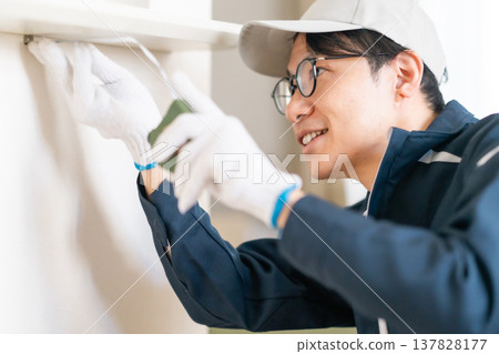 On-site inspection for home renovation. An engineer accurately measures the wall dimensions using a measuring tape. 137828177