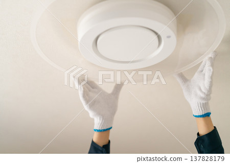 一張工人將照明燈具更換為LED燈的圖片。圖片顯示的是工人在安裝吸頂燈時的雙手（未顯示臉部）。 137828179