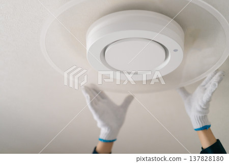 一張工人將照明燈具更換為LED燈的圖片。圖片顯示的是工人在安裝吸頂燈時的雙手（未顯示臉部）。 137828180