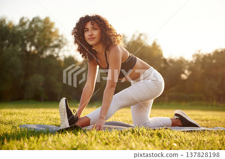 Stretching the legs. Young fitness woman is on the field outdoors Stretching the legs. Young fitness woman is on the field outdoors 137828198