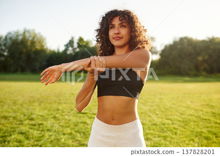 Getting ready, warm up exercises. Young fitness woman is on the field outdoors Getting ready, warm up exercises. Young fitness woman is on the field outdoors 137828201