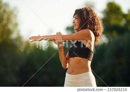 Hands exercises. Young fitness woman is on the field outdoors Hands exercises. Young fitness woman is on the field outdoors 137828219