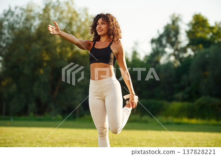 Hands exercises. Young fitness woman is on the field outdoors Hands exercises. Young fitness woman is on the field outdoors 137828221