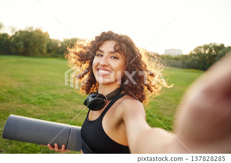 Photo for social media, doing selfie. Young fitness woman is on the field outdoors Photo for social media, doing selfie. Young fitness woman is on the field outdoors 137828285