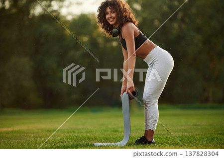 Rolling off yoga mat. Young fitness woman is on the field outdoors Rolling off yoga mat. Young fitness woman is on the field outdoors 137828304