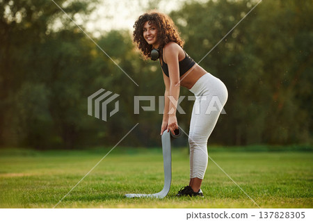 Rolling off yoga mat. Young fitness woman is on the field outdoors Rolling off yoga mat. Young fitness woman is on the field outdoors 137828305