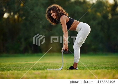 Rolling off yoga mat. Young fitness woman is on the field outdoors Rolling off yoga mat. Young fitness woman is on the field outdoors 137828306
