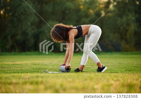 Rolling off yoga mat. Young fitness woman is on the field outdoors 137828308