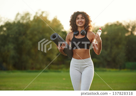 Hydration conception, holding bottle of water. Young fitness woman is on the field outdoors Hydration conception, holding bottle of water. Young fitness woman is on the field outdoors 137828318
