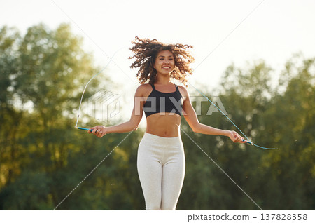 Jumping rope, active. Young fitness woman is on the field outdoors 137828358