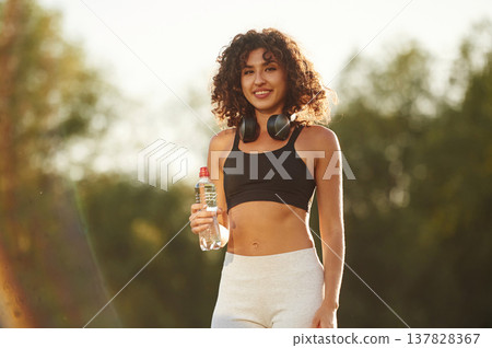 Break time, with bottle of water. Young fitness woman is on the field outdoors 137828367