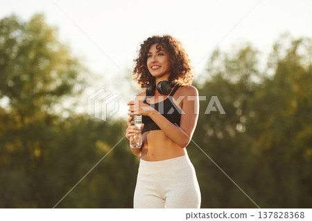 Break time, with bottle of water. Young fitness woman is on the field outdoors 137828368