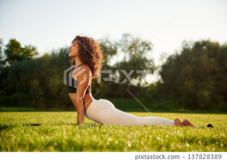 Spine yoga exercise. Young fitness woman is on the field outdoors Spine yoga exercise. Young fitness woman is on the field outdoors 137828389