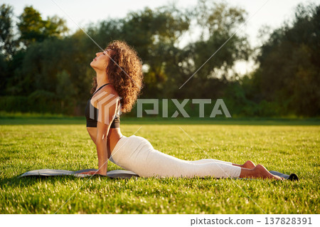 Spine yoga exercise. Young fitness woman is on the field outdoors Spine yoga exercise. Young fitness woman is on the field outdoors 137828391