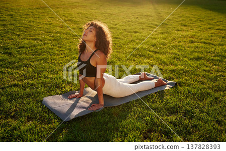 Spine yoga exercise. Young fitness woman is on the field outdoors Spine yoga exercise. Young fitness woman is on the field outdoors 137828393